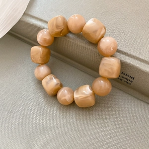Détail d'un bracelet en acrylique ambré avec des perles carrées sur un fond de livre texturé
