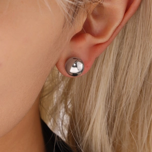 Minimalist silver steel spherical stud earrings shown on model ear for high-quality look
