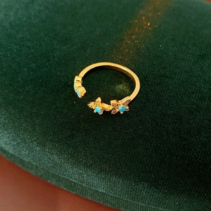 Détail d'une bague vintage dorée avec papillon et turquoise sur boîte en velours