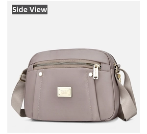 Detail of taupe nylon shoulder bag with golden fashion plaque and front zipper pockets