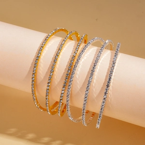 Five-piece set of gold and silver layered rhinestone tennis bangles on a display stand