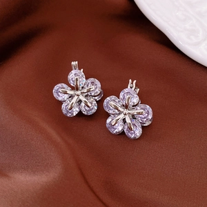 Gros plan de boucles d'oreilles fleur en argent avec cristaux de zircon violets sur satin