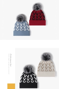 Detail of color-block knit beanies with faux fur pompom in blue, red, black, and beige
