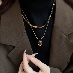 Double-layered gold-plated necklace with tiger eye beads and pendant on a female model