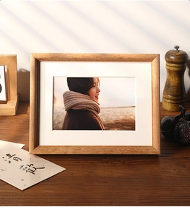 Detailed view of a solid wood photo frame with white matting under soft window shadows