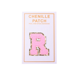 Macro shot of pink chenille letter R patch with gold glitter edge and peel-and-stick backing