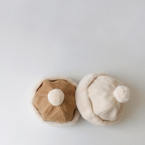 Detailed view of suede and faux fur winter hats with plush pom-poms for children