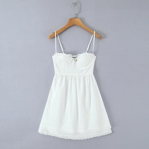 Detail of white lace camisole dress with floral embroidery and bow strap design