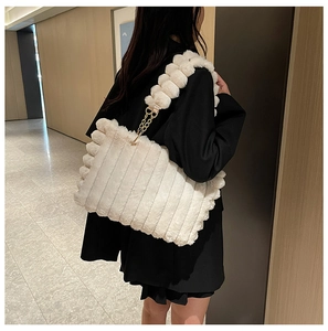 Detail of white plush tote bag with striped texture and elegant gold chain strap