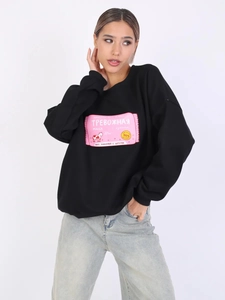 Detail des rosa russischen Textdrucks auf einem schwarzen Sweatshirt mit Rundhalsausschnitt