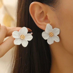 Élégantes boucles d'oreilles fleurs blanches avec détail doré sur un mannequin