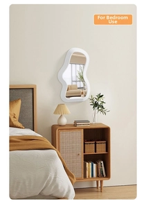 Close-up of cloud-shaped irregular white wavy frame mirror in a cozy bedroom setting