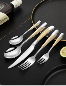 Close-up of 5-piece stainless steel cutlery with gold diamond-pattern handles on dark table