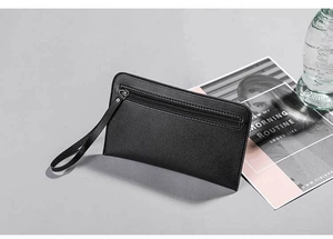 Close-up of black leather clutch bag with silver zipper and practical wrist strap
