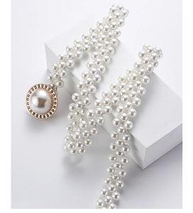Detailed close-up of a white faux pearl belt featuring a rhinestone-edged round buckle