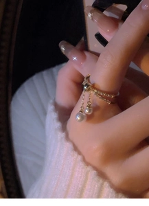 Detail of gold-plated double-layer ring with pearls and pavé zircons worn on finger