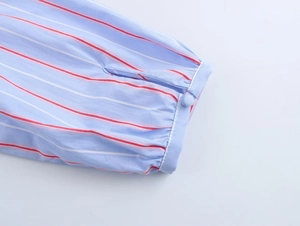 Close-up of shirt cuff with red and white horizontal stripes and button detail