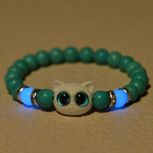Luminous cat head bead bracelet featuring glowing blue tiger eye stones in dark lighting
