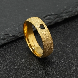 Detailed shot of golden frosted ring featuring a hollow heart cutout on dark slate