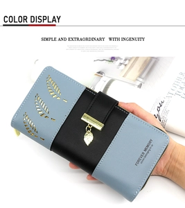 Detail of blue and black long wallet featuring hollow leaf pattern and metal leaf charm