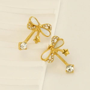 Detail of gold bow earrings with shell inlay, star charms, and sparkling zircon crystals