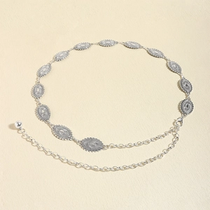 Detailed close-up of retro silver metal chain belt with embossed oval geometric patterns