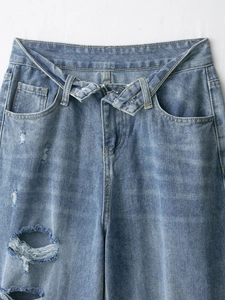 Dettaglio della vita e degli strappi su jeans in denim azzurro dallo stile vissuto