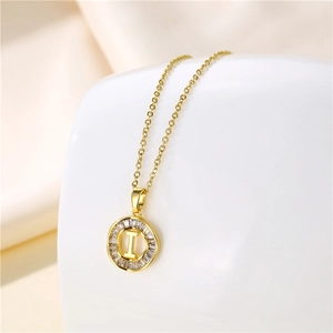 Macro shot of 18K gold plated circle pendant with Zirconia and letter I on silk fabric