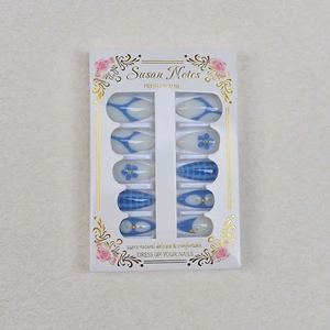 Detail of white and blue almond fake nails with floral patterns and gold accents