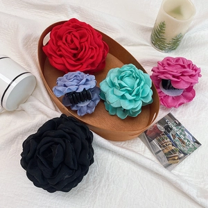 Elegant rose flower hair claw clips in five colors on a decorative wooden tray