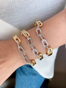 Close-up of three stacked geometric chain bracelets with pavé zircons and two-tone finish