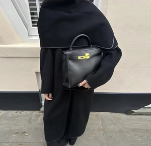Close-up of minimalist black leather handbag paired with an oversized black wool coat