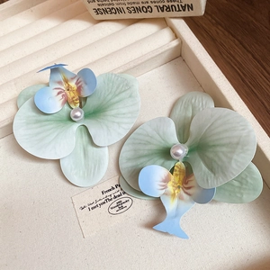 Detailed macro view of orchid flower hair clip with pearl center on jewelry tray
