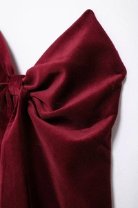 Détail d'un haut bandeau en velours bordeaux avec un grand nœud et une texture raffinée