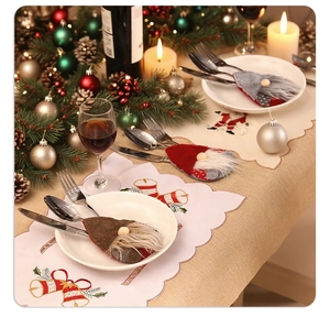 Christmas table setting with gnome cutlery holders and embroidered placemats on a festive table