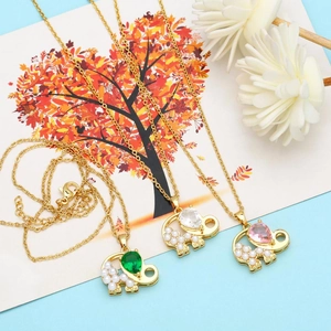 Detailed view of gold elephant necklaces with emerald, clear, and pink gems and white pearls