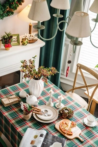 Detail of Christmas green plaid tablecloth with festive ceramic decor and berry vase