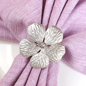 Matte silver flower napkin ring with five petals on purple linen fabric background