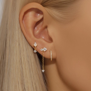 Detail of three-piece gold starburst earring set with cz chain tassels on model ear