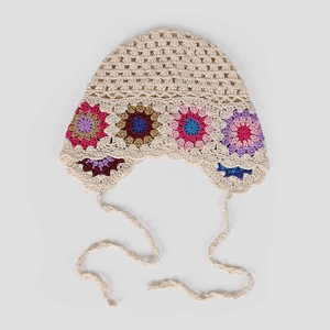 Close-up of handmade crochet hollow bonnet with colorful floral embroidery and ribbon straps