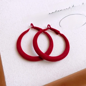 Macro detail of red velvet-textured hoop earrings showing the soft flocking and vibrant color