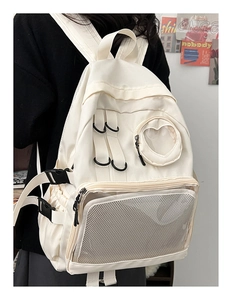Detail of cream backpack featuring transparent heart window and mesh pocket on model