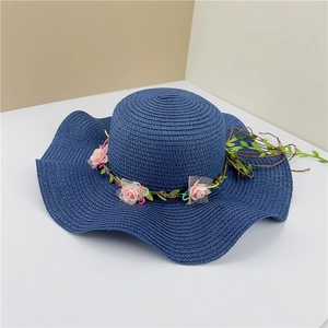 Navy blue wide-brim woven straw hat featuring pink rose floral trim and foliage decoration