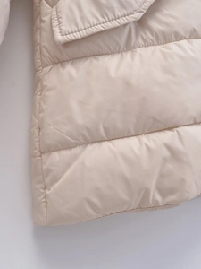 Detailed view of beige padded jacket featuring horizontal quilting and glossy finish