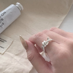 Detail of silver knot ring on model hand with minimalist cotton pouch backdrop