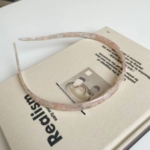 Detail van roze en witte acetaat haarband met marmertextuur op een wit boekoppervlak