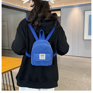 Rear view of model wearing a mini Klein blue corduroy backpack with embroidered text