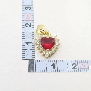 Macro view of gold heart pendant with red gem and size measurement scales