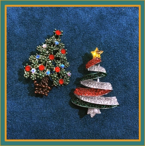 Detailed macro view of green and red crystal Christmas tree brooches on blue velvet
