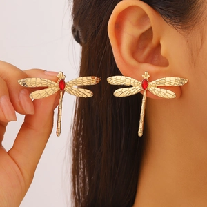 Détail de boucles d'oreilles libellule avec cristal rouge et ailes dorées sur mannequin